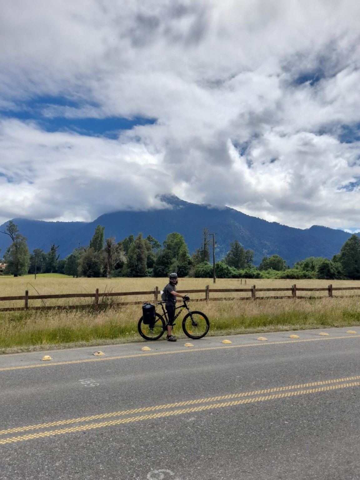 Ciclista y bicicleta con alforjas ante las montañas